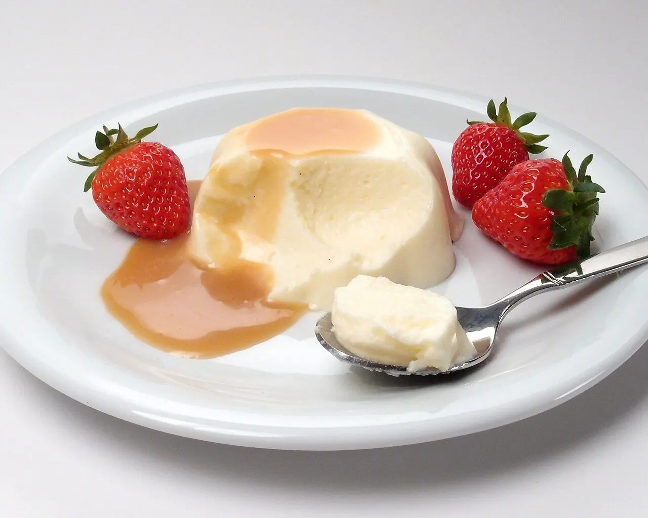 A serving of Bavarian cream with strawberries and caramel sauce. Bavarian cream is a milk-based, gelatin-set vanilla dessert with whipped cream. Despite its name, it is believed to have originated in